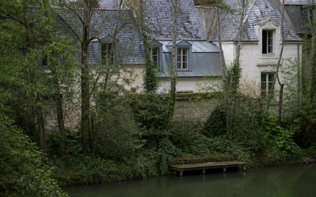 Maisons aux toits pentus bordant l’Erdre, reflets de l’eau et rives boisées au premier plan