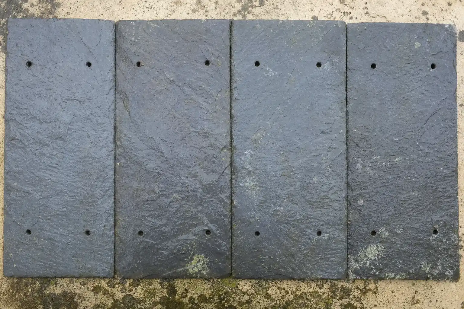 Ardoises naturelles à plat, épaisseur irrégulière et arêtes fendues, reflets bleus sur la face mouillée